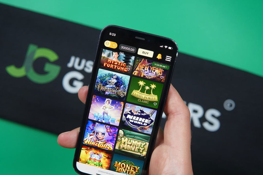 Patrik Lidin holding an iPhone with the Wild World Casino game library page loaded on the webpage.