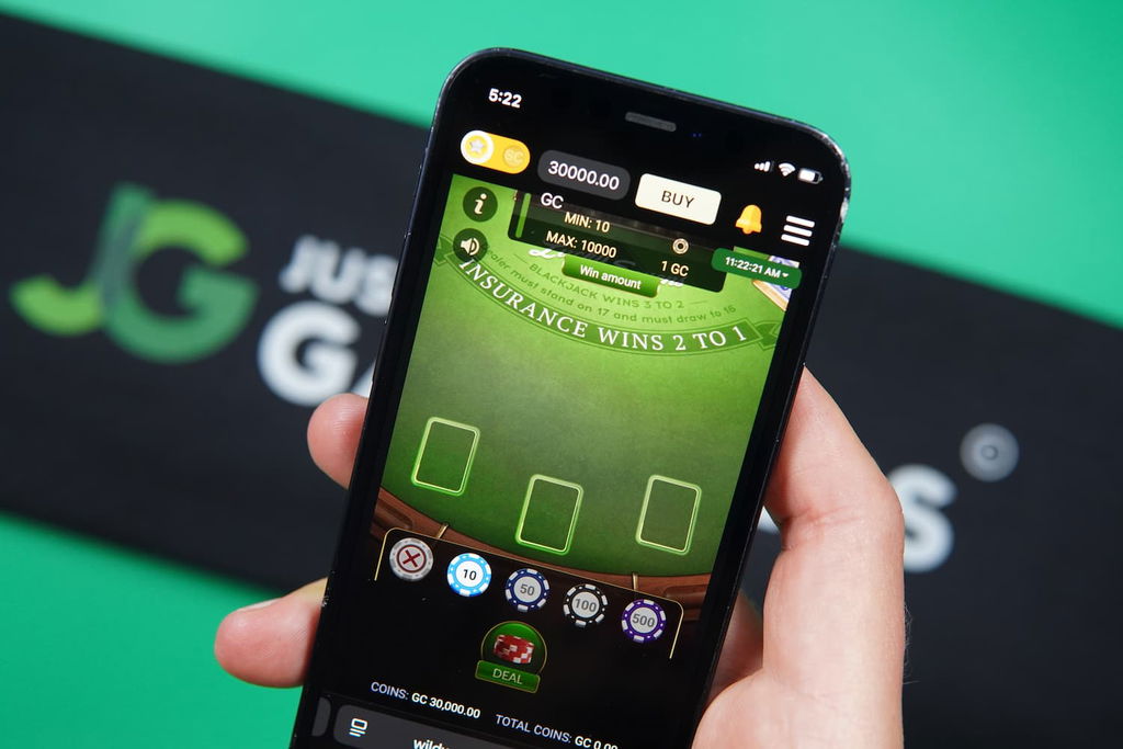 Patrik Lidin holding an iPhone with the Wild World Casino in-game blackjack page loaded on the webpage.