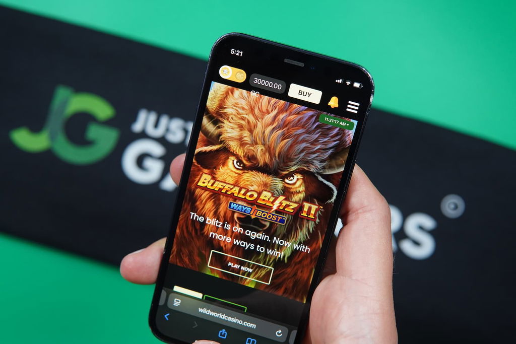 Patrik Lidin holding an iPhone with the Wild World Casino landing page loaded on the webpage.