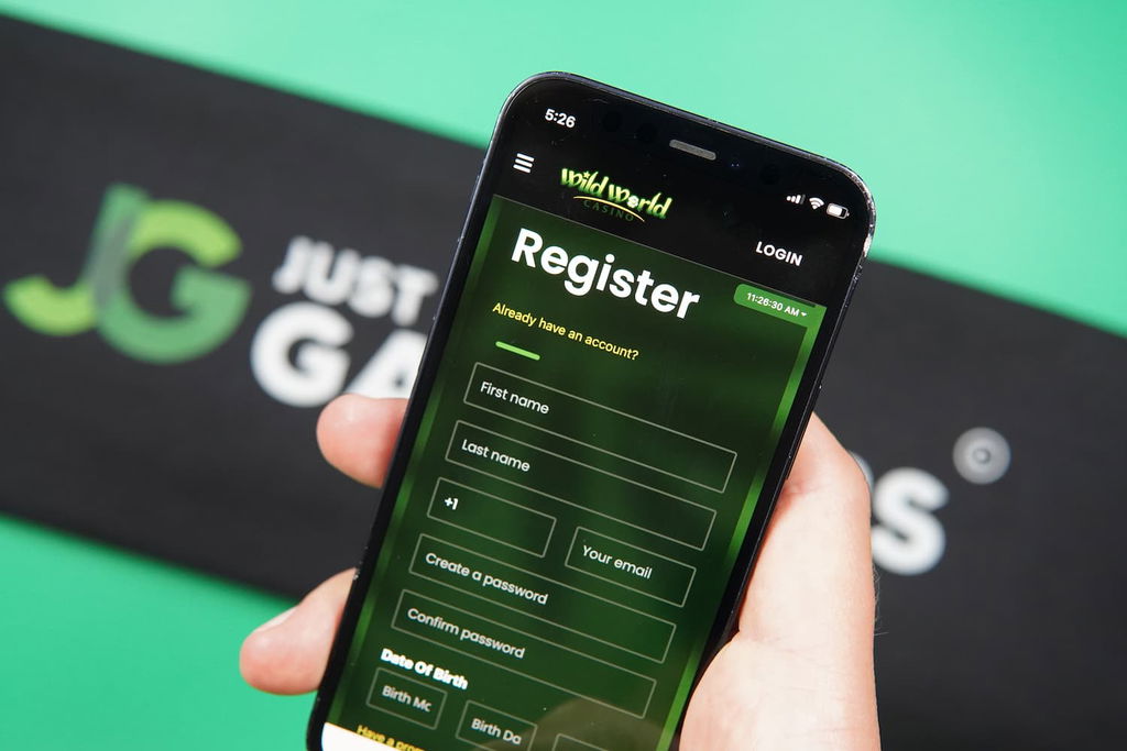 Patrik Lidin holding an iPhone with the Wild World Casino registration page loaded on the webpage.