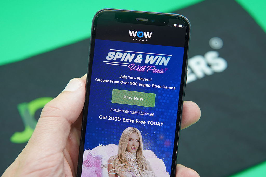 Patrik Lidin holding an iPhone showing the third best sweepstakes casino for beginners WOW Vegas.