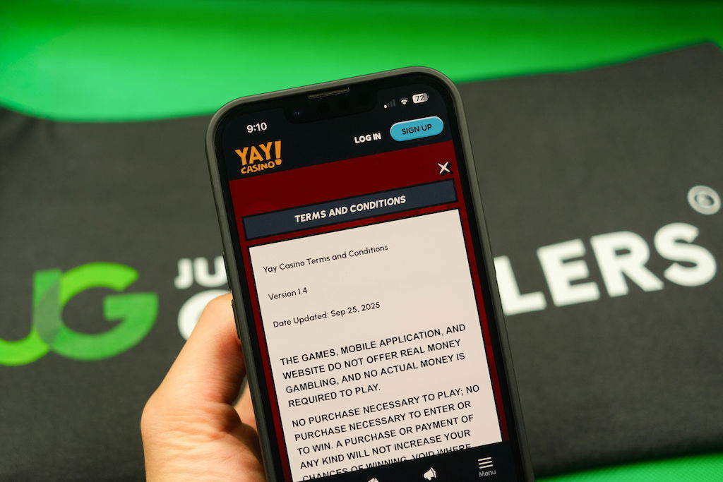 Patrik Lidin holding an iPhone with the Yay casino Terms and Conditions page loaded on the webpage.