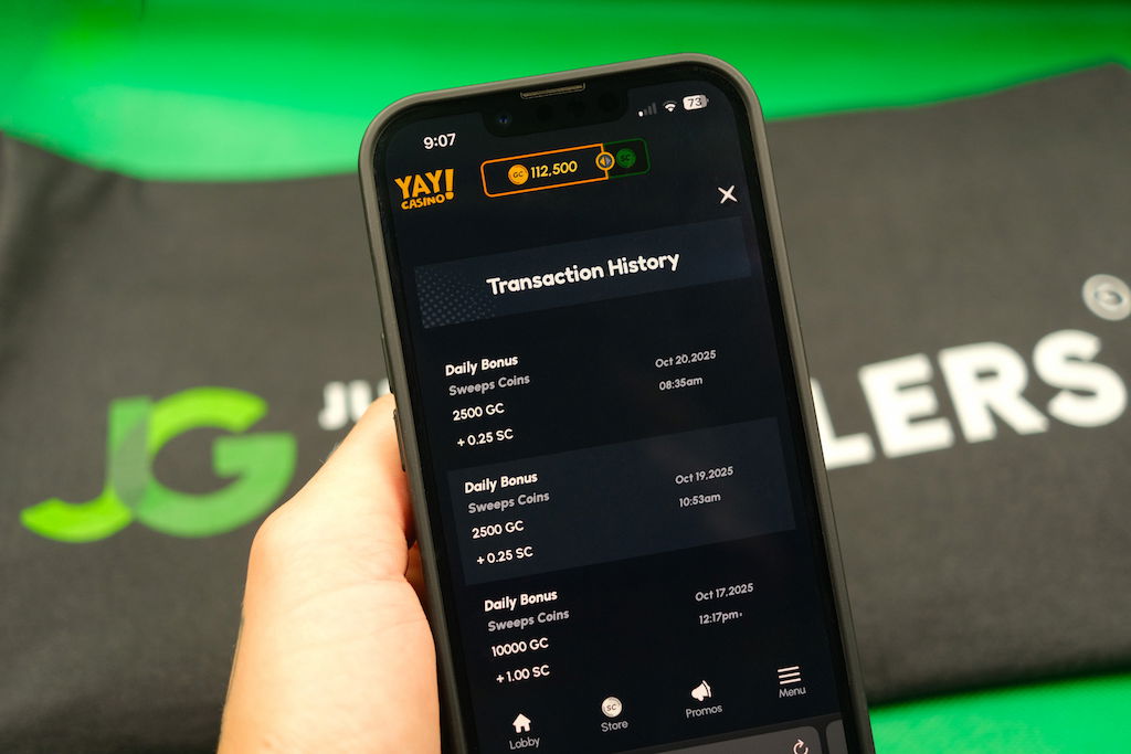 Patrik Lidin holding an iPhone with the Yay casino transaction history page loaded on the webpage.