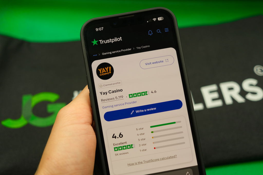 Patrik Lidin holding an iPhone with the Yay casino Trustpilot ratings page loaded on the webpage.
