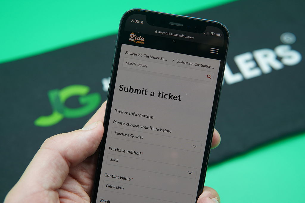 Patrik Lidin holding an iPhone while using the Zula Casino customer support.