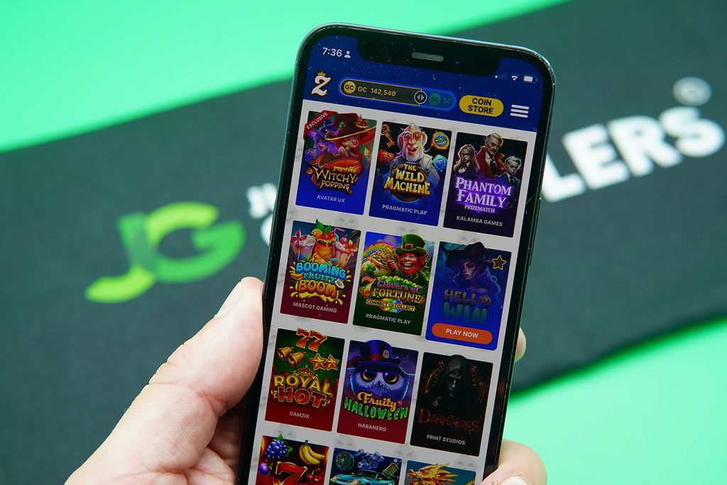 Patrik Lidin holding an iPhone with Zula Casino game library showing.