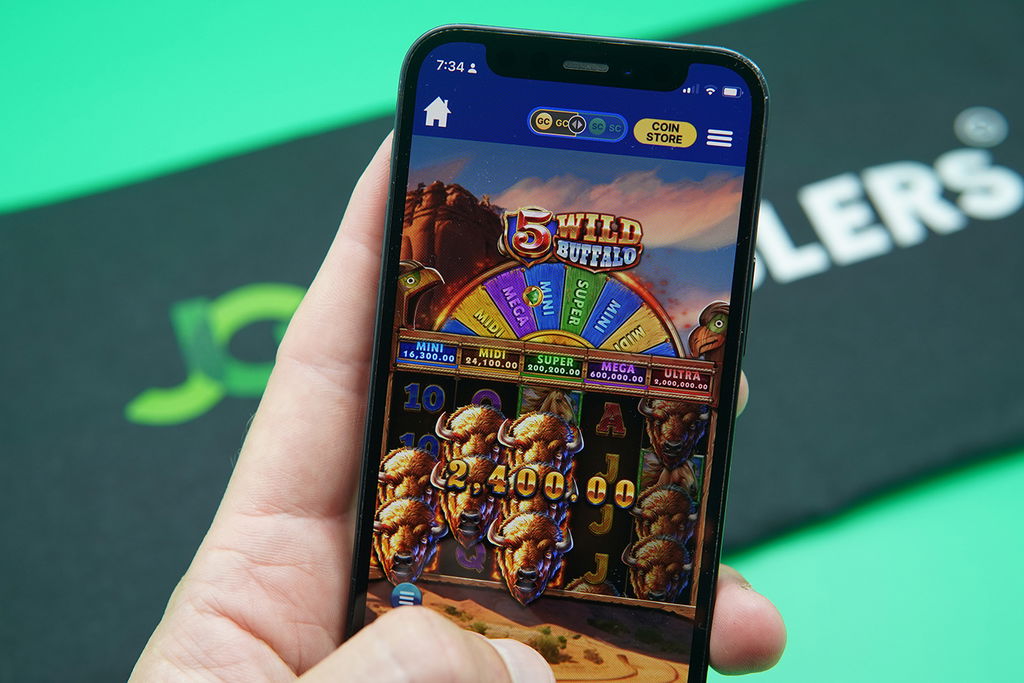 Patrik Lidin holding an iPhone with Zula Casino game 5 Wild Buffalo showing.