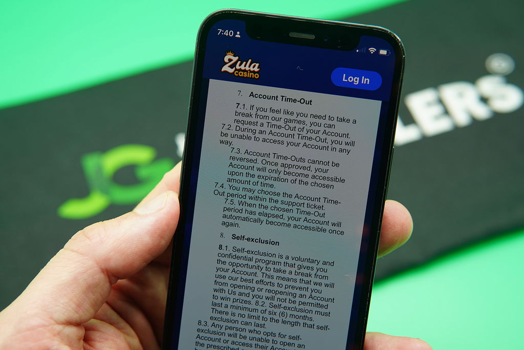 Patrik Lidin holding an iPhone with the Zula Casino responsible gambling page showing.